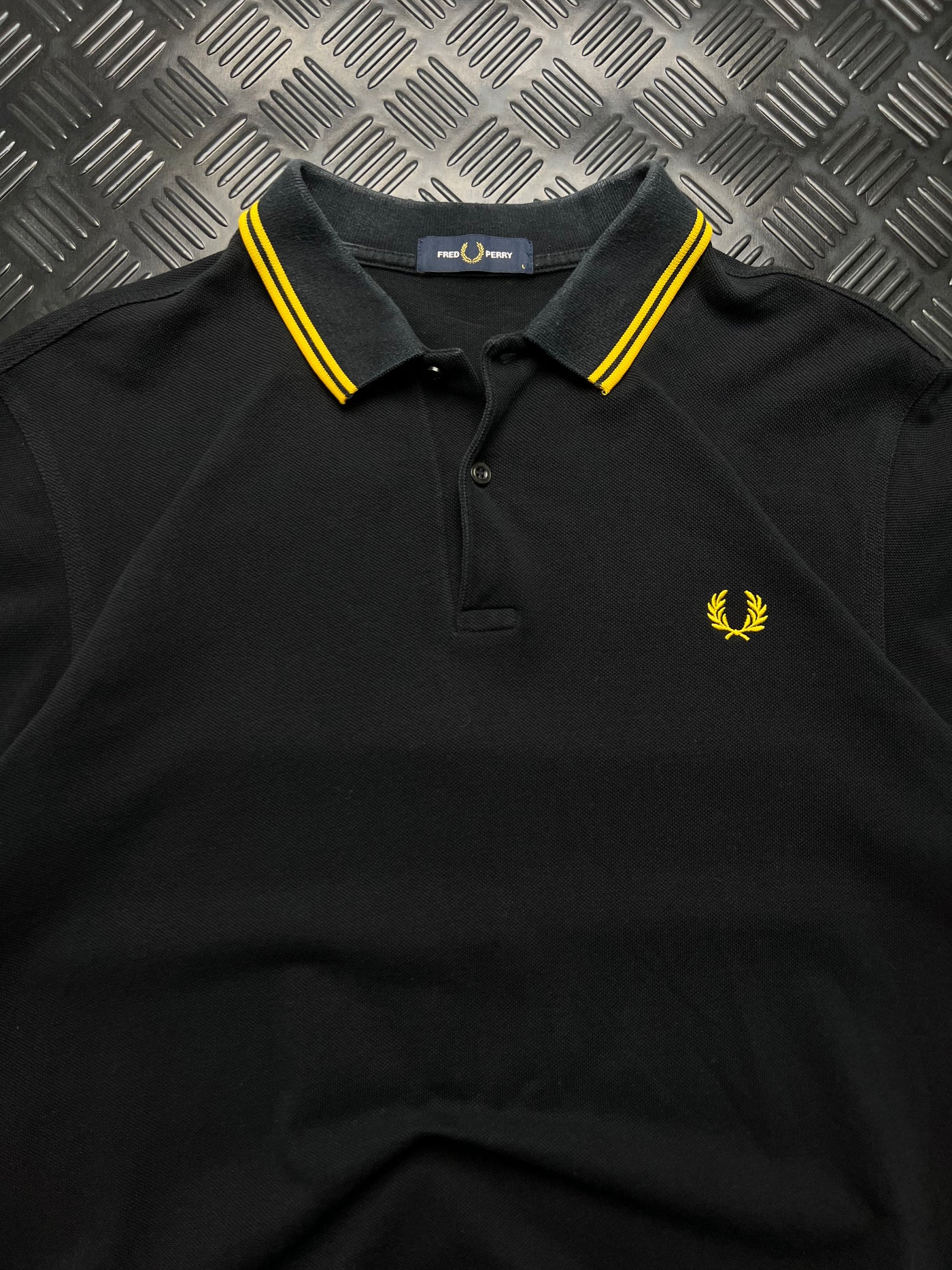 Detalle de polo Fred Perry negro con ribetes amarillos talla L
