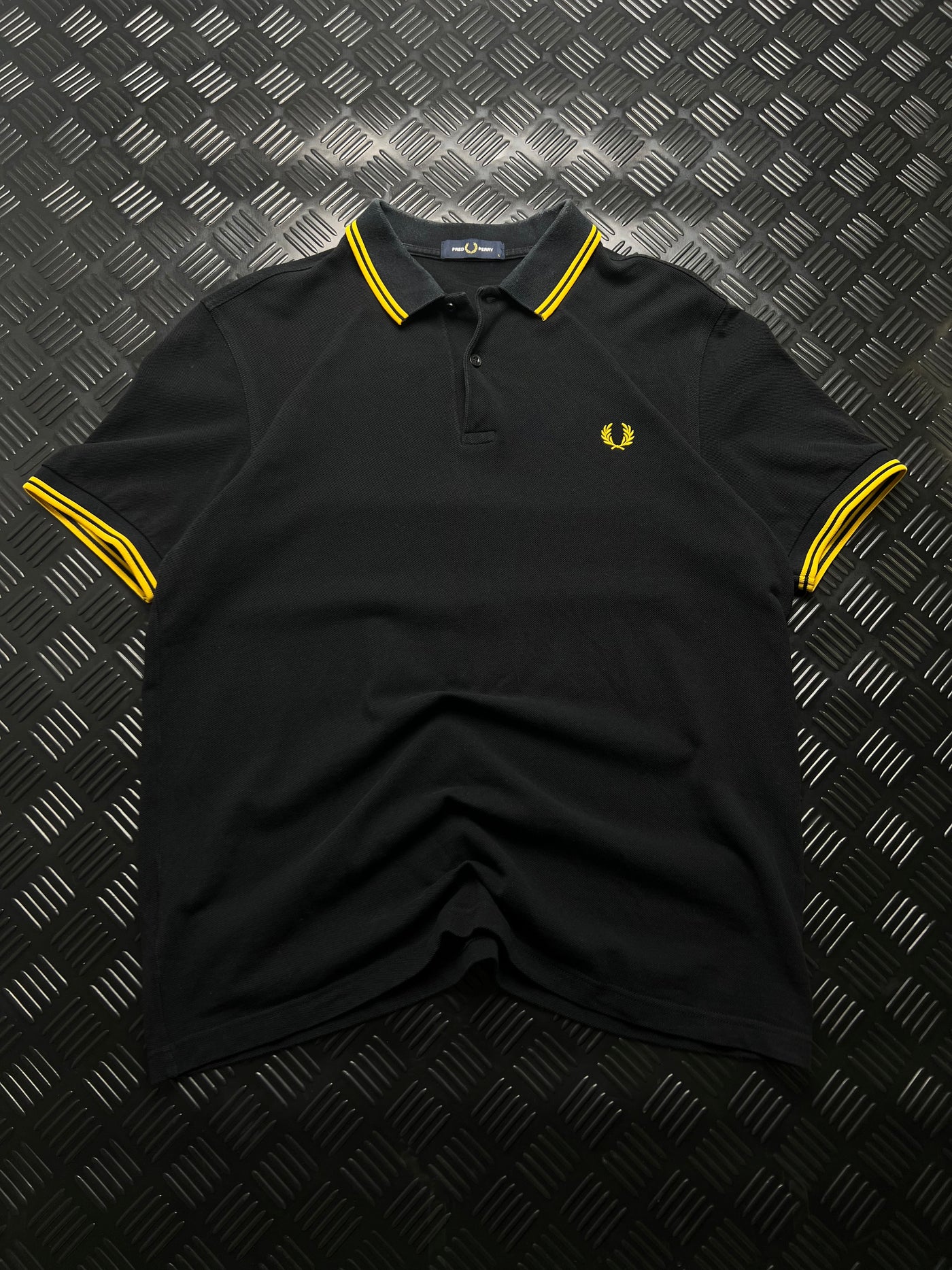 Vista frontal de polo Fred Perry negro y amarillo