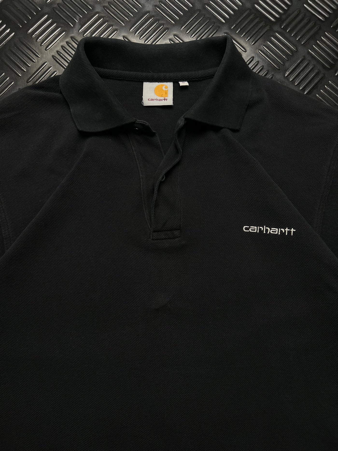 Detalle de etiqueta y logotipo bordado de polo Carhartt