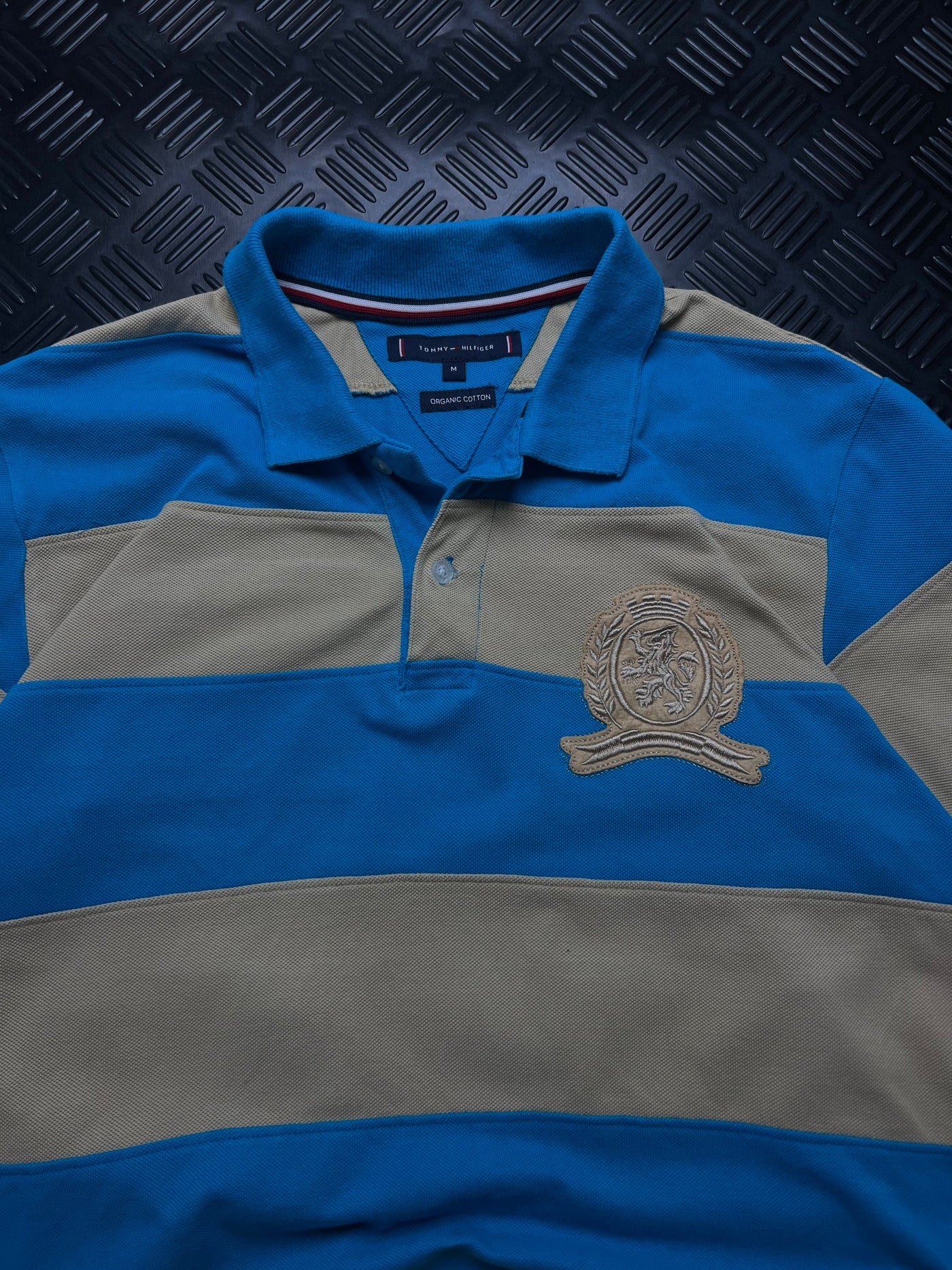 Detalle de etiqueta talla M y escudo bordado de polo Tommy Hilfiger