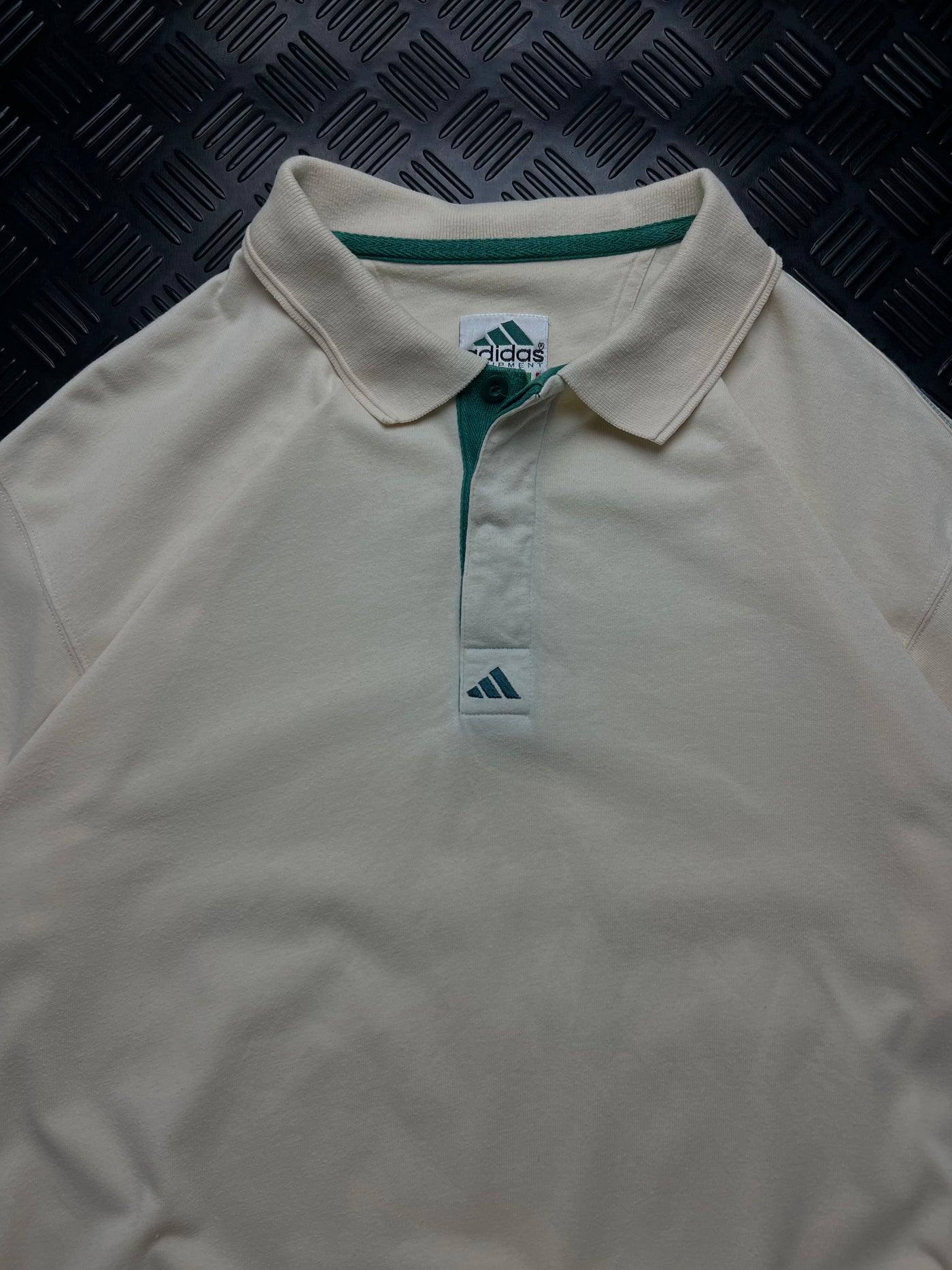 Detalle frontal de polo Adidas Equipment blanco y verde