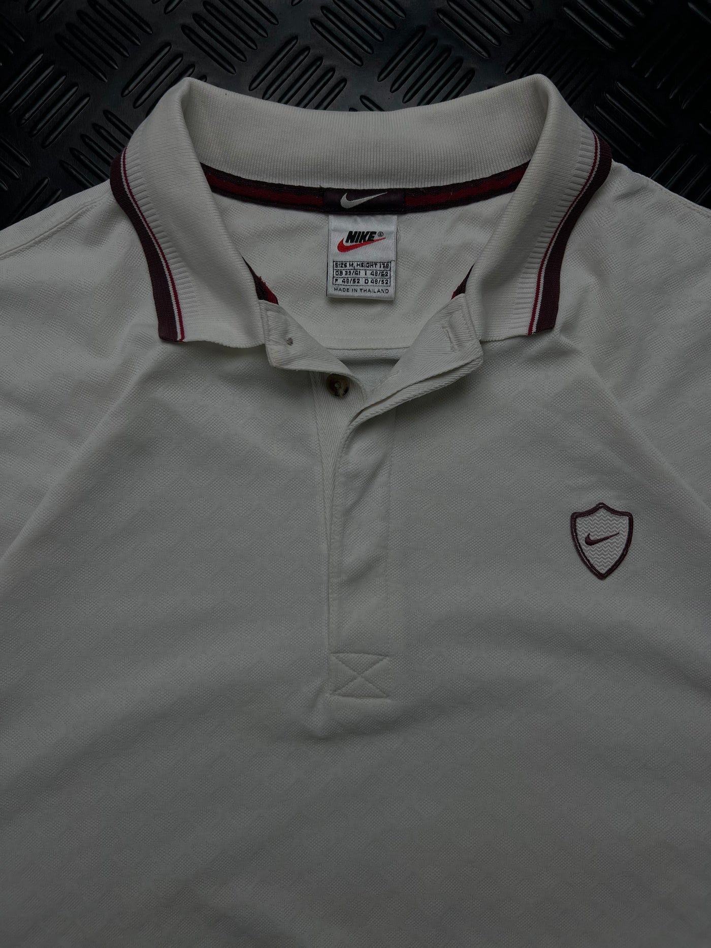 Detalle de etiqueta talla M y escudo bordado de polo Nike vintage