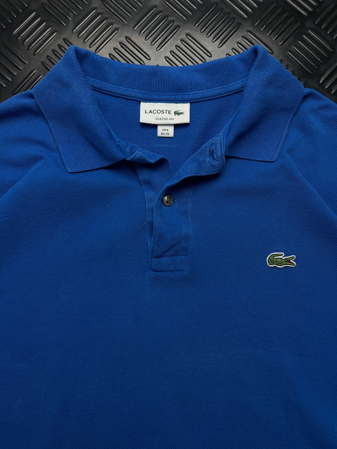 Detalle de etiqueta talla XL y cocodrilo Lacoste